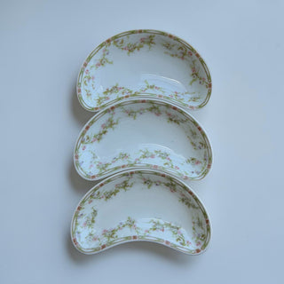 Her Good Eye antique kidney-shaped porcelain serving dishes with pink floral accents and green vine border.