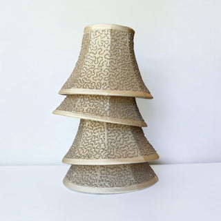 Her Good Eye champagne gold bell-shaped lamp shades stacked with intricate beadwork and shimmering sequin details.