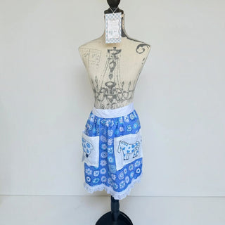 Her Good Eye blue floral half apron with white waistband, lace trim, and animal motif pockets on a dress form