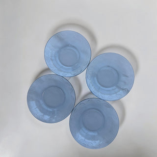 Her Good Eye set of four blue glass dessert plates with embossed leaf pattern around the rim.