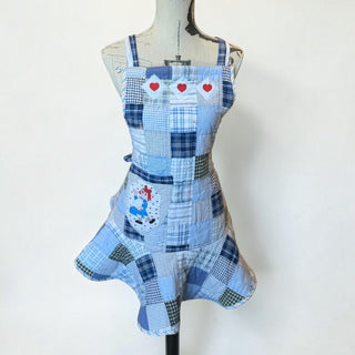 Her Good Eye blue quilted patchwork apron with red heart appliqués and a vintage character patch on a mannequin.