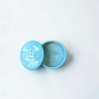 Her Good Eye sky blue round trinket dish with ship motif lid and marbled interior. Ideal for jewelry storage.