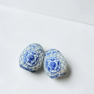 Her Good Eye pair of blue and white porcelain decorative eggs with intricate cut-out floral designs.
