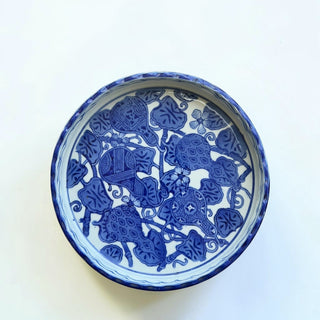 Her Good Eye blue and white ceramic serving dish with scalloped edge and intricate floral and turtle motifs.
