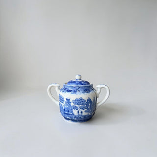 Her Good Eye blue and white ceramic sugar bowl with lid, featuring classic Willow pattern and two handles.