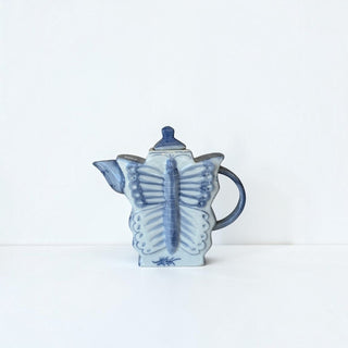 Her Good Eye handcrafted porcelain teapot in a blue and white butterfly shape with a glazed finish.
