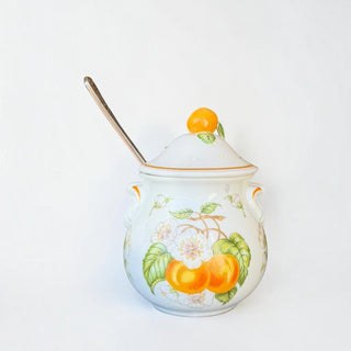 Her Good Eye ceramic lidded serving jar with hand-painted orange citrus motif, scroll handles, and matching spoon.