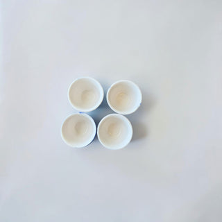 Her Good Eye set of four white ceramic egg cups with blue floral and windmill motifs in a vintage Dutch style.