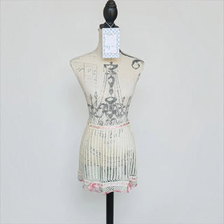 Her Good Eye cream crochet mini skirt with blush pink satin ribbon trim and bow details on a mannequin