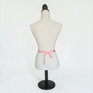 Her Good Eye cream crochet mini skirt featuring a blush pink satin ribbon tie at the waist on a mannequin.