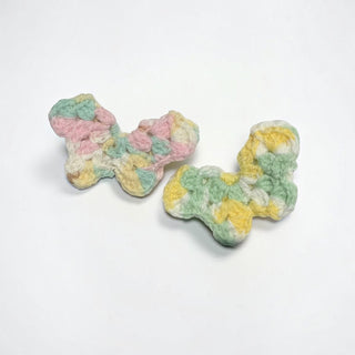 Her Good Eye handmade crochet butterfly hair clips in variegated pastel yellow, mint green, and white yarn.