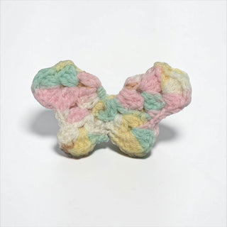 Her Good Eye handmade crochet butterfly in variegated pastel pink, yellow, and mint green yarn for DIY projects.
