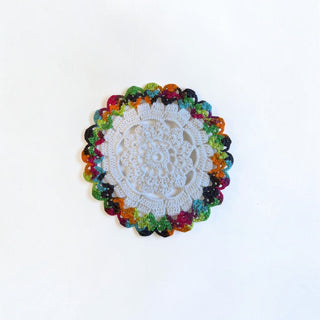 Her Good Eye handmade crochet table doily with intricate white center and vibrant multi-colored scalloped border
