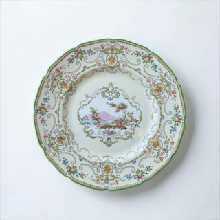 Her Good Eye decorative porcelain plate with pastoral landscape and floral border, scalloped green trim.