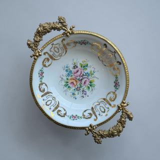 Her Good Eye decorative white porcelain bowl with ornate gold handles, hand-painted floral bouquet, and gilded rim.