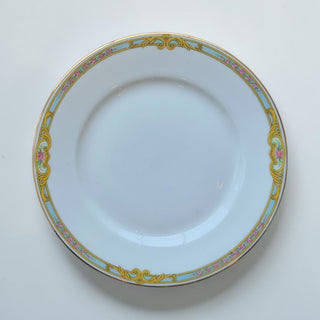 Her Good Eye decorative porcelain dinner plate with floral accents, blue and gold scrollwork, and pink roses.