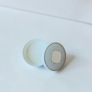 Her Good Eye decorative round tin with pale blue textured pattern, ornate center, and gold trim. Ideal for storage or display.