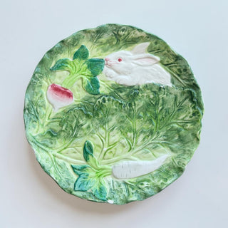 Her Good Eye embossed ceramic plate with white rabbit, radish, and carrot amongst green cabbage leaves.
