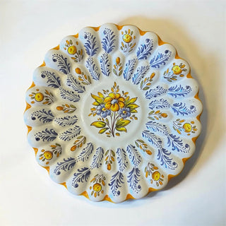 Her Good Eye hand-painted ceramic egg platter with blue foliage and yellow floral motifs on a scalloped white base.