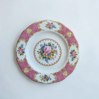 Her Good Eye decorative dinner plate with pink roses, blue forget-me-nots, and yellow flowers. Scalloped gold border and pink rim with gold scrollwork.
