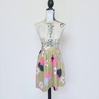 Her Good Eye vintage-inspired half apron in khaki with bold pink floral and navy blue polka-dot print on a mannequin.