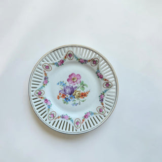 Her Good Eye decorative porcelain plate with a central floral bouquet and a pierced lattice border with gold trim.