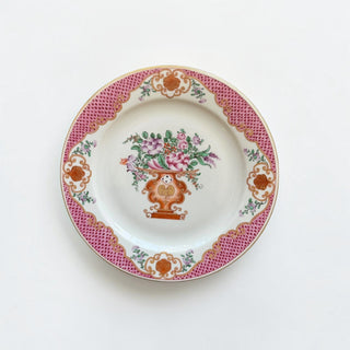 Her Good Eye vintage porcelain plate with hand-painted floral urn motif, pink lattice border, and gold trim.