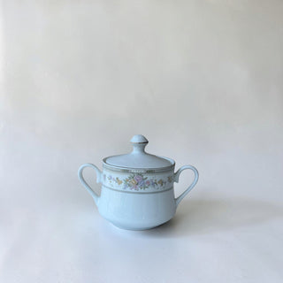 Her Good Eye light blue porcelain sugar bowl with lid, featuring a pastel floral band and gold trim. Two handles for serving.
