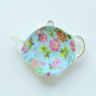 Her Good Eye floral teapot shaped tea bag holder dish with pink, orange, and purple flowers on a sky blue background.