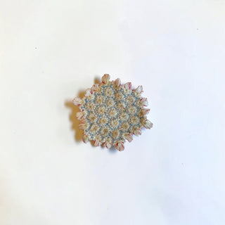 Her Good Eye handcrafted textile coaster with cream and pink ruffled floral needlework and blue stitching details.