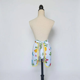 Her Good Eye vintage style white half apron with a colorful fruit print and yellow trim tied on a mannequin