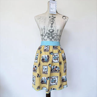 Her Good Eye yellow half apron with garden scene print and sky blue trim. Cotton blend.