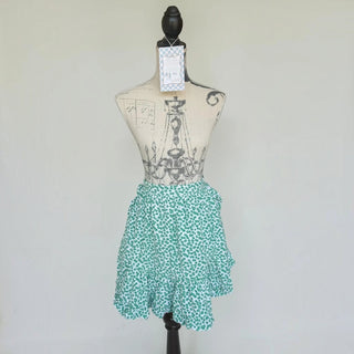 Her Good Eye green and white floral print half apron with a ruffled hem on a vintage dress form mannequin