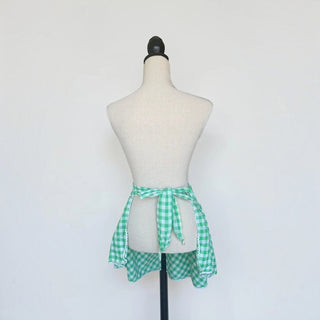 Her Good Eye green and white gingham waist apron with smocking and white lace trim on a mannequin