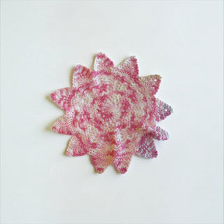 Her Good Eye handmade crochet doily in pink and white with a star-inspired floral pattern for vintage home decor.
