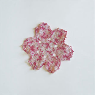 Her Good Eye handmade crochet doily in variegated pink and white yarn with an intricate floral openwork design.