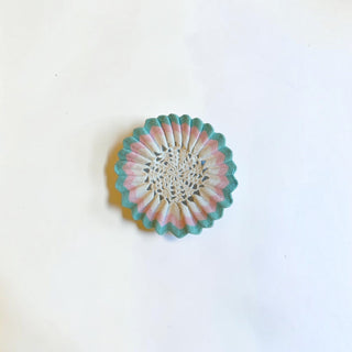 Her Good Eye handmade crochet doily with a creamy white center and pleated pastel pink and mint green scalloped edge.