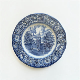 Her Good Eye blue and white ceramic plate featuring an Independence Hall historical scene with ornate floral border