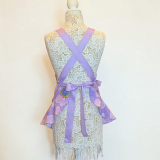 Her Good Eye lavender floral kitchen apron with ruffled hem and crisscross back straps on a lace mannequin