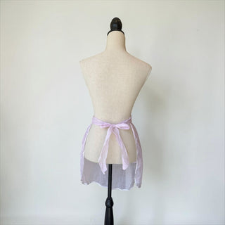 Her Good Eye sheer lavender half apron with white lace trim and tie waist, displayed on a mannequin.