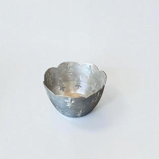 Her Good Eye decorative metal bowl with a brushed silver finish, scalloped edges, and embossed fleur-de-lis motifs.