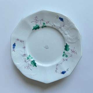 Her Good Eye octagonal porcelain plate with hand-painted green, blue, and purple floral vine design and embossed rim.