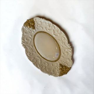 Her Good Eye ornate oval serving tray in cream with intricate raised scrollwork and gold-toned accents.