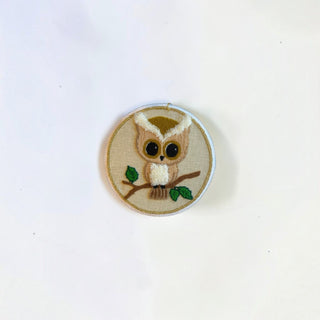 Her Good Eye handcrafted owl embroidery hoop art featuring a whimsical owl in tan and brown threads on a cream fabric.