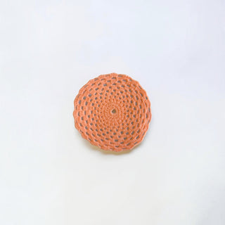 Her Good Eye handmade peach circular crochet coaster with intricate open-weave pattern and scalloped edges.