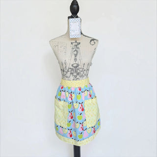Her Good Eye blue cotton waist apron featuring a colorful pear print and yellow floral pockets on a dress form.