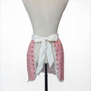 Her Good Eye pink half apron with cherry and strawberry print, white eyelet lace trim and tie.