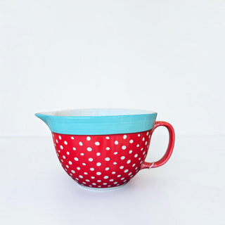 Her Good Eye ceramic mixing bowl in red with white polka dots, featuring a turquoise rim, handle, and pouring spout.
