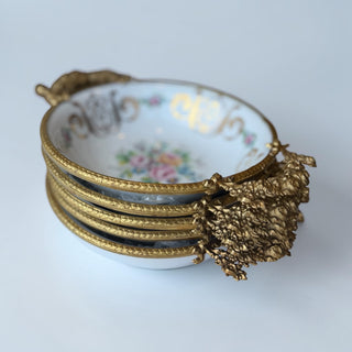 Her Good Eye white porcelain decorative bowl with ornate gold handles and floral bouquet painting.