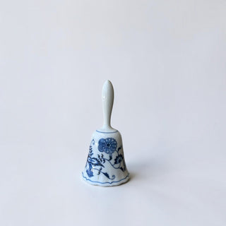 Her Good Eye porcelain hand bell with blue and white floral pattern and scalloped edge on a white background.